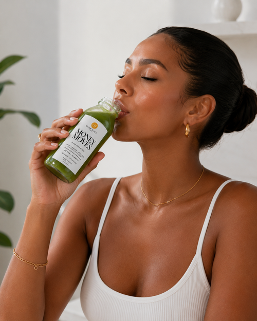 A woman in a white ribbed tank top drinks from a clear bottle of Money Moves green juice.